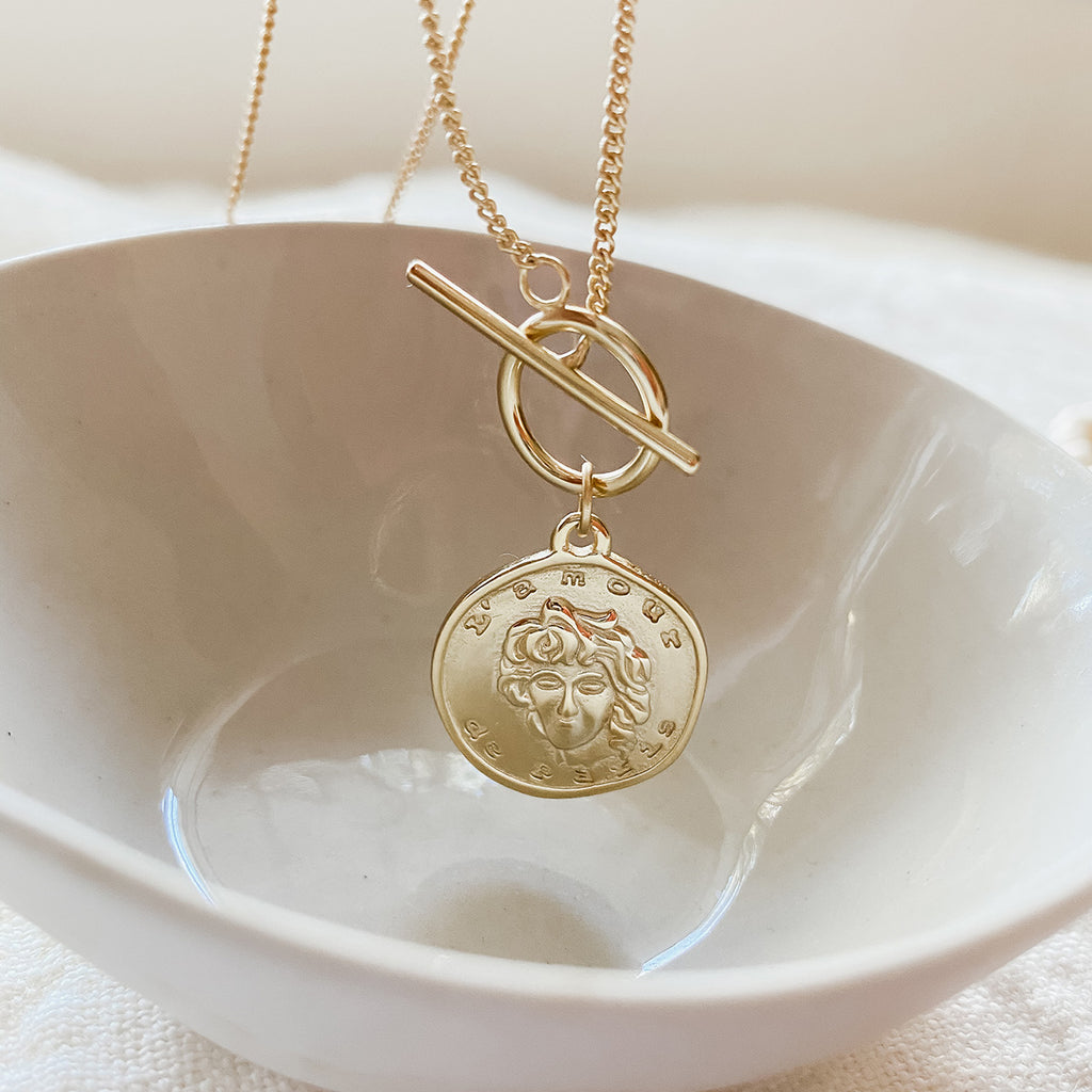 a gold filled necklace hanging over of bowl